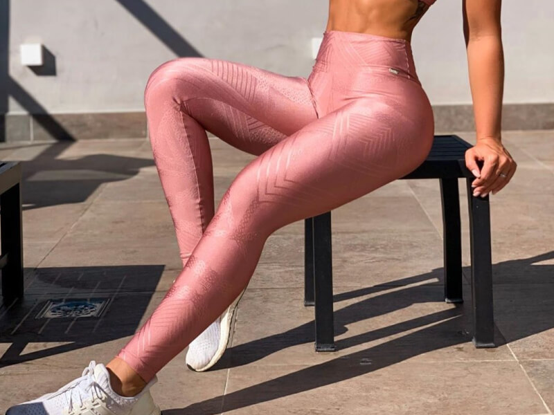 pernas de mulher sentada usando legging rosa