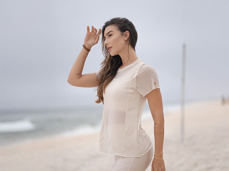 Modelo feminina em praia com camiseta clara