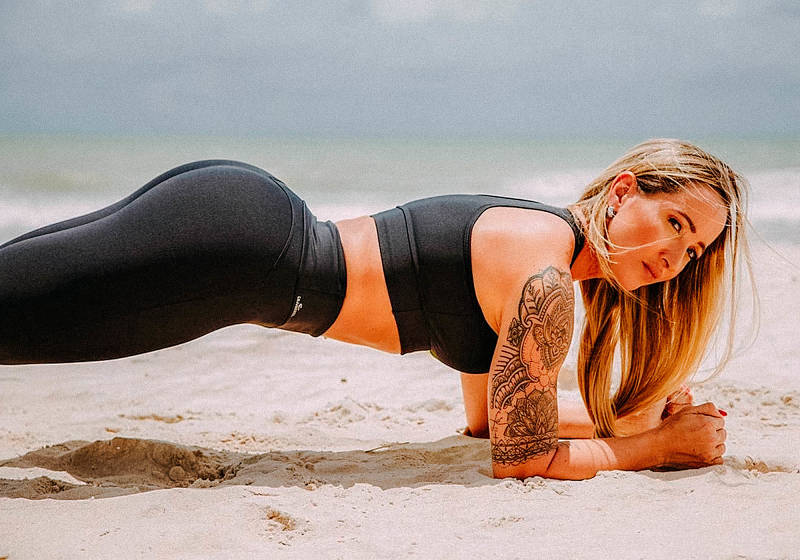 mulher fazendo exercício prancha na areia da praia