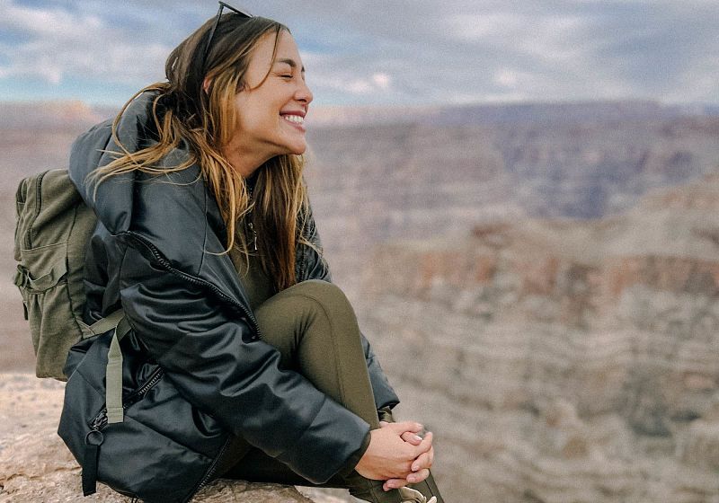 mulher sentada em canyon com roupa de trilha