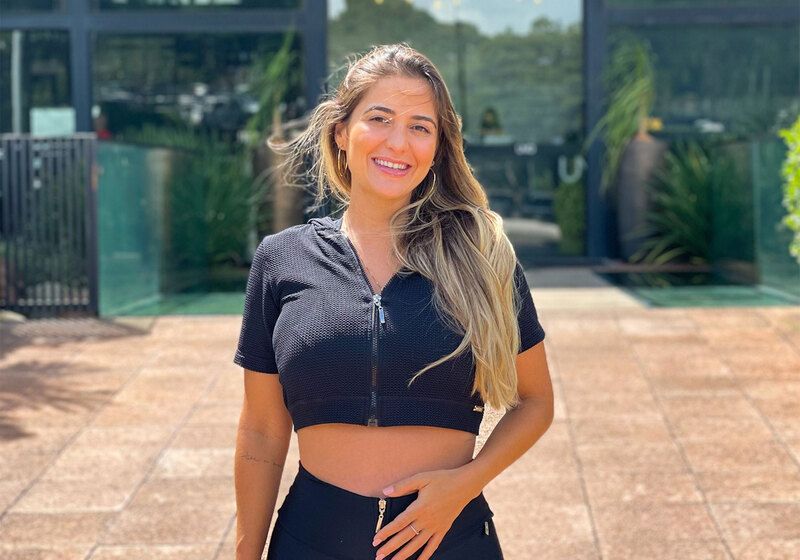 blogueira fitness olhando para câmera e sorrindo usando cropped curto de zíper