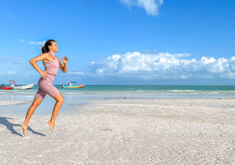 mulher correndo na praia usando biquini