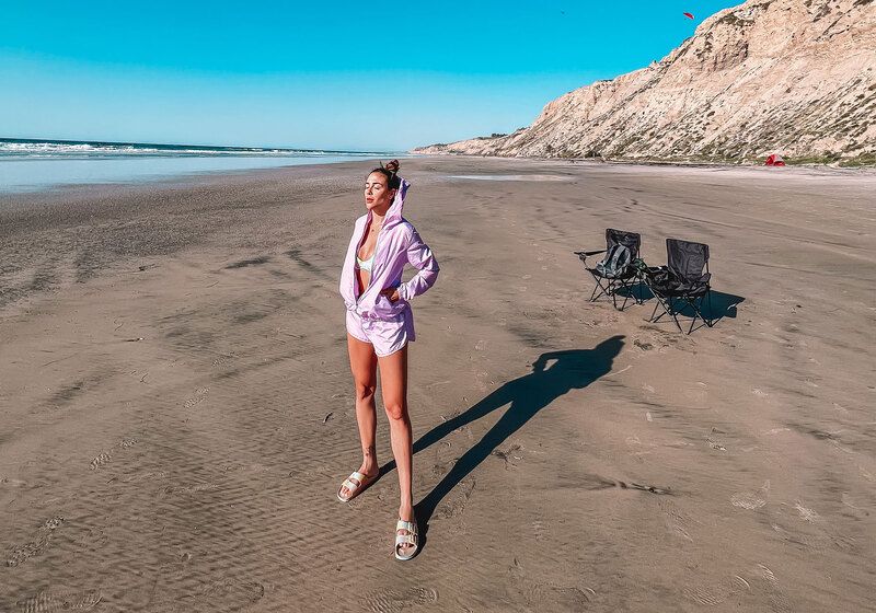 mulher na praia em dia frio usando uma blusa corta vento