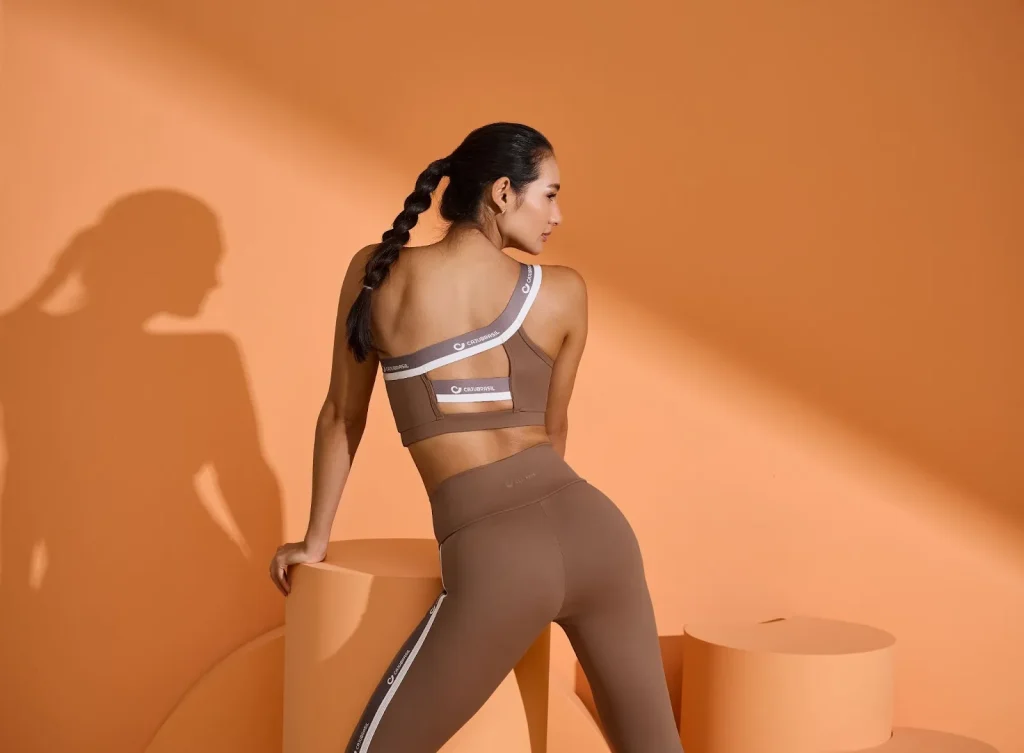 Modelo posa com conjunto marrom fitness em estúdio, exemplo de foto profissional para vender roupas.