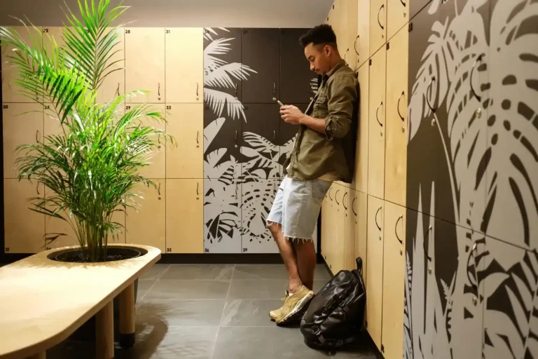 Armários de vestiário com design moderno e planta decorativa, compondo a decoração de loja fitness.