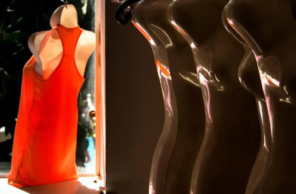 Manequins e peça fitness em destaque sob iluminação, compondo a decoração de loja fitness.