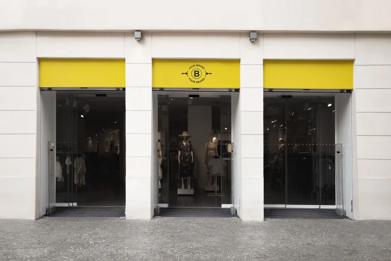 Fachada de loja com vitrine de roupas femininas, ilustrando espaço para aplicação de logo de loja de roupas fitness.
