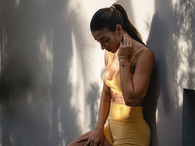 Mulher em roupa fitness amarela posando ao ar livre