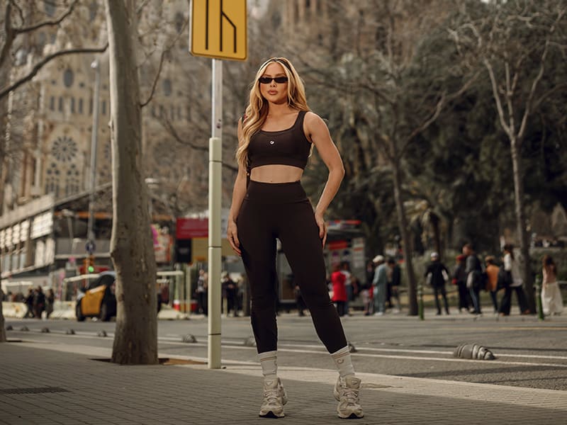 Mulher em roupa esportiva preta em uma rua movimentada.