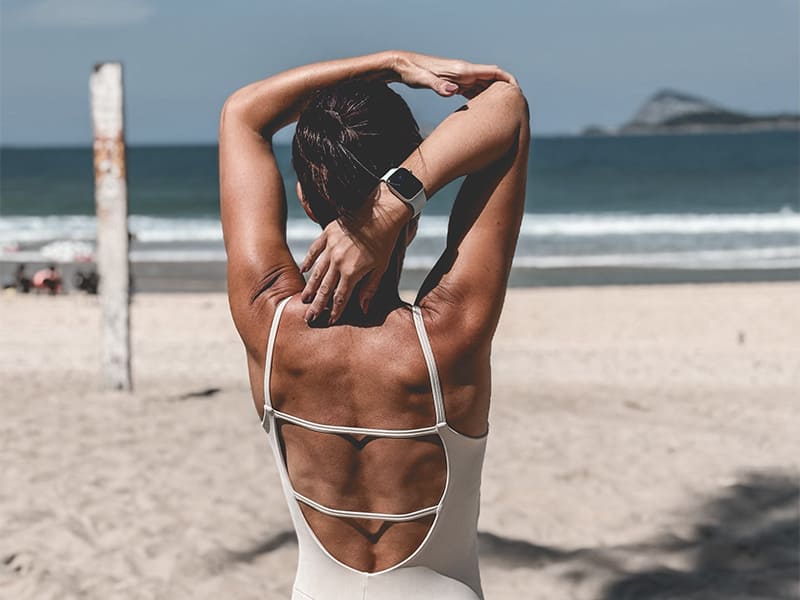Mulher de costas na praia com maiô elegante